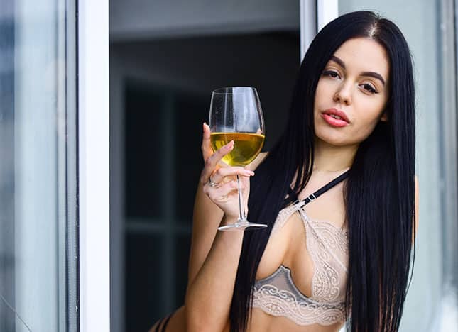 Frau in BH mit einem Weinglas in der Hand